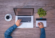 Top view of a man working on a laptop while drinking coffee