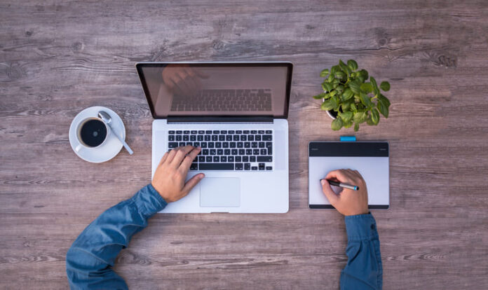 Top view of a man working on a laptop while drinking coffee