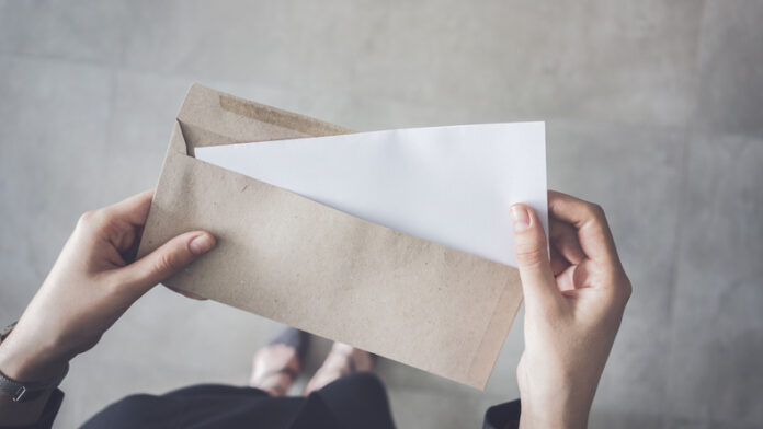 woman holding white folded a4 paper and brown envelope