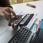 woman working with finance calculate on calculator and using computer laptop and document data chart in office room.