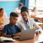 student and teacher using laptop