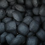 Close-up of an oval-shaped unburned charcoal grill drenched in fuel. Top view.