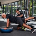 Personal trainer helping an old man in the gym