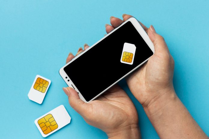 Front view of hands holding smartphone sim cards