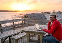 A man working on a laptop outdoors at the beach. A man working on a laptop outdoors at the beach.