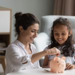 mother and kid dropping cash into piggy bank