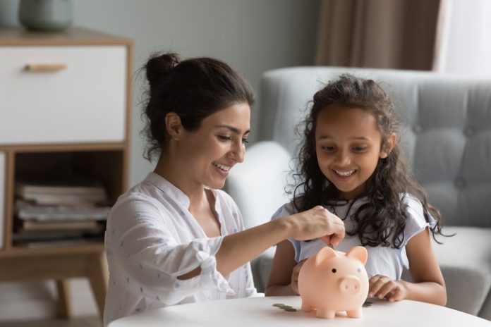 mother and kid dropping cash into piggy bank