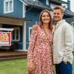 Couple standing behind their new home