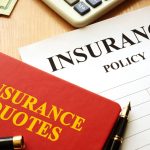 Insurance quotes book and policy on a desk.