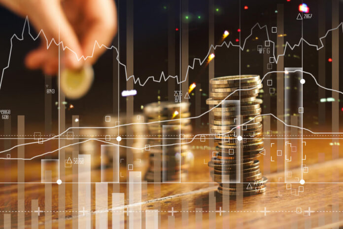 Double exposure. Hand holding golden coin of graph and rows with coins on wooden table. Finance and business concept.