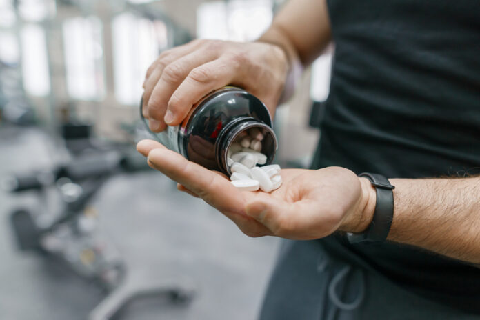 Sporty muscular man arms showing sports and fitness supplements