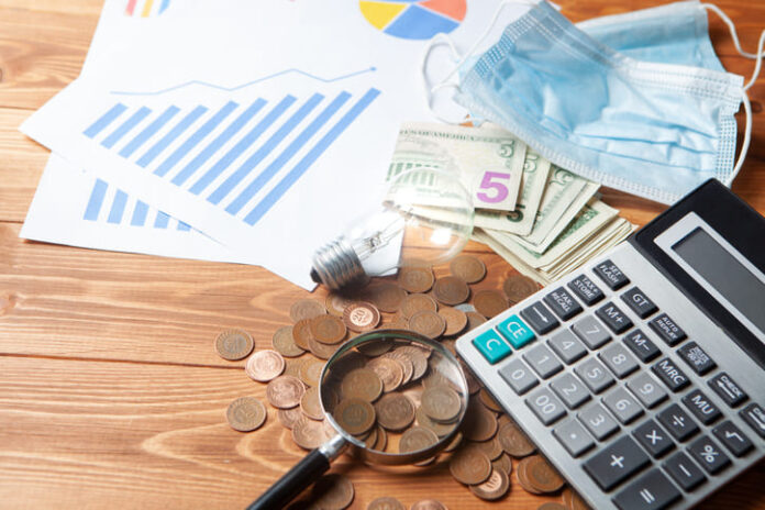 Pandemic cost with calculator, magnifier and coins