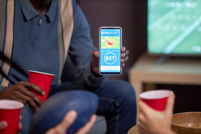 Close up of man holding smartphone with sports bets app