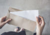 woman holding white folded a4 paper and brown envelope