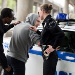 Policeman and policewoman arresting young man in hoodie