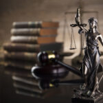 Themis, gavel, scale and legal books on the desk.