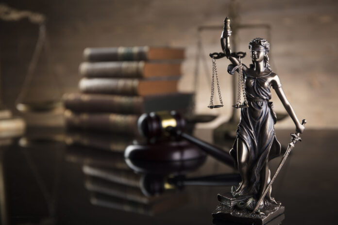 Themis, gavel, scale and legal books on the desk.