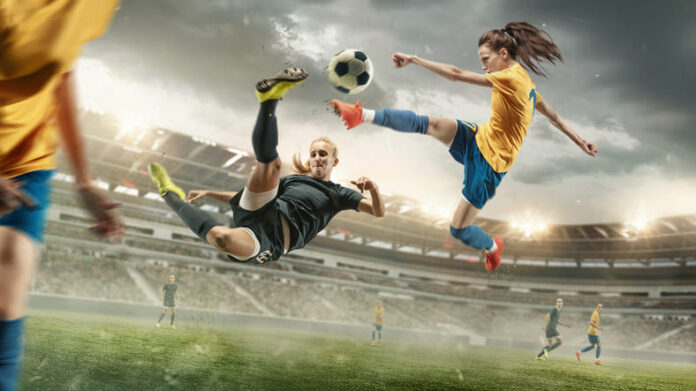 Female football players kicking ball at the stadium