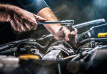 Auto mechanic working on car engine in mechanics garage