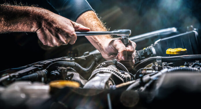 Auto mechanic working on car engine in mechanics garage