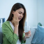 Asian beautiful woman feel terrible toothache after drink cold water.