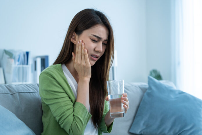 Asian beautiful woman feel terrible toothache after drink cold water.