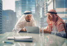 Two Successful Emirati Businessmen in White Traditional Kandura Sitting in Office Meeting