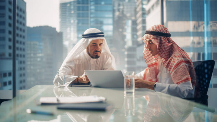 Two Successful Emirati Businessmen in White Traditional Kandura Sitting in Office Meeting