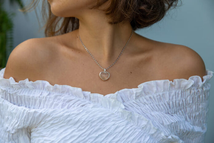 Closed up of trendy woman outfit wearing white shirt and heart shape necklace.