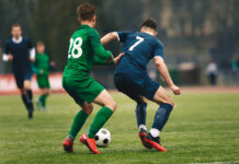 Adult football competition. Soccer football player dribbling a ball and kick a ball during match in the stadium