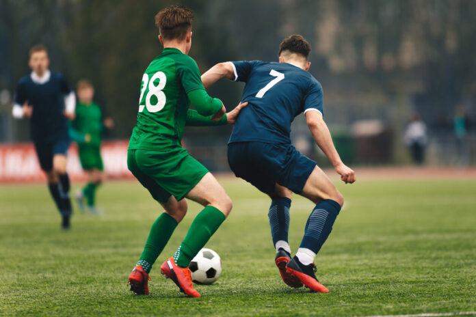 Adult football competition. Soccer football player dribbling a ball and kick a ball during match in the stadium