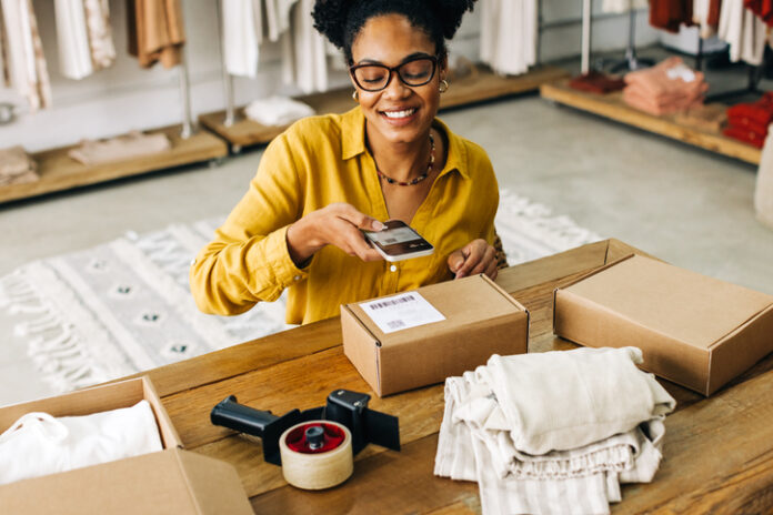 Female dropshipper uses a smartphone to scan the QR code for an online clothing order