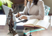 Statue of Justice with scales and lawyer working on a laptop