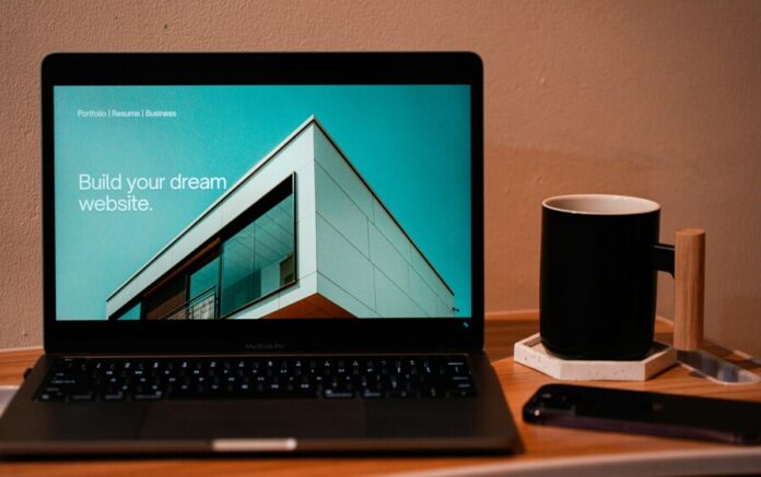 Build your dream website for your future. A laptop, MacBook, on top of a portable table with coffee tea mug on the side.