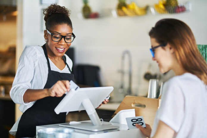 Waitress swiping customers bank card on pos terminal at restaurant