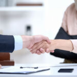 Insurance agent shaking hand with woman in arm sling