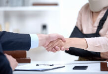 Insurance agent shaking hand with woman in arm sling