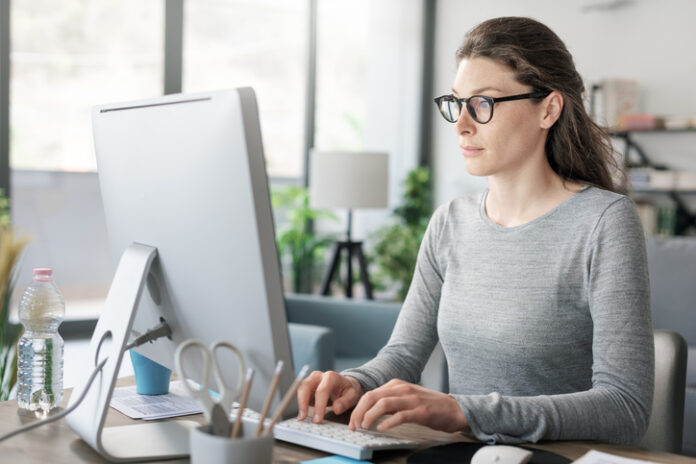 Professional woman sitting at desk and connecting with her computer