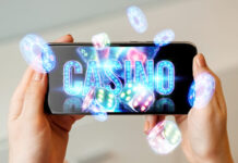 In a man's hand a smartphone with playing neon cards, chips, dice