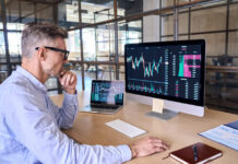 Trader using computer analyzing digital stock market trading graph.