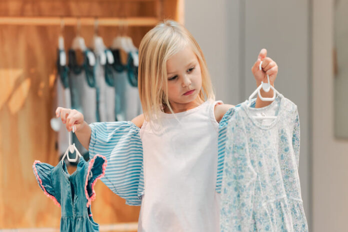 Child, fashion and shopping while choosing kids clothing in a shop