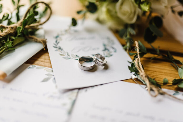 Stylish rings, flowers on wooden table background.