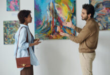 Young man discussing modern art with young woman during exhibition in gallery