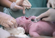 Newborn being examined by doctor using stethoscope