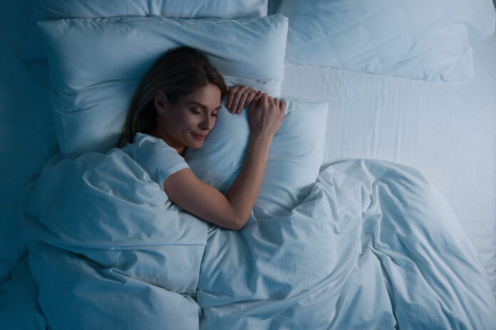 Woman sleeping in bed at night, above view.