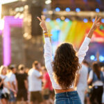 Back view of young woman at summer beach music festival.