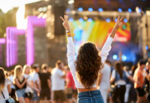 Back view of young woman at summer beach music festival.