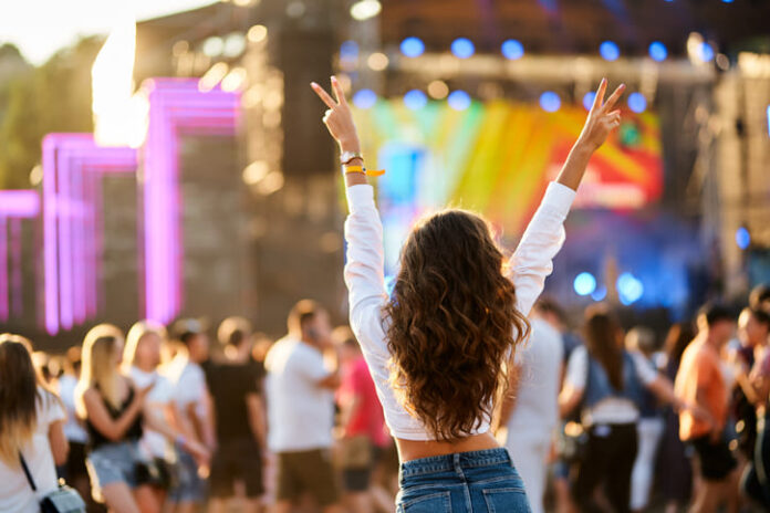 Back view of young woman at summer beach music festival.