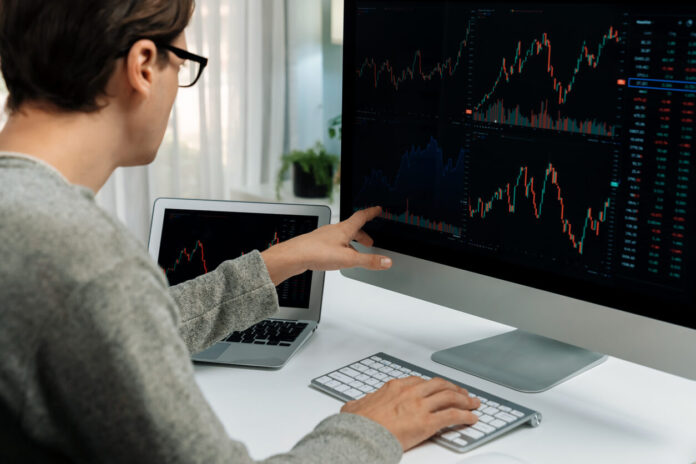 Investors pointing interesting stock exchange on pc with laptop