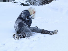 A woman slips on the winter road.